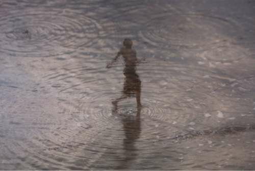 Through reflections of beachgoers seen in the wet sands