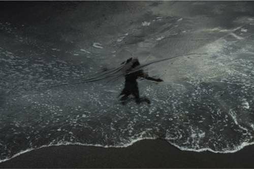 Through reflections of beachgoers seen in the wet sands